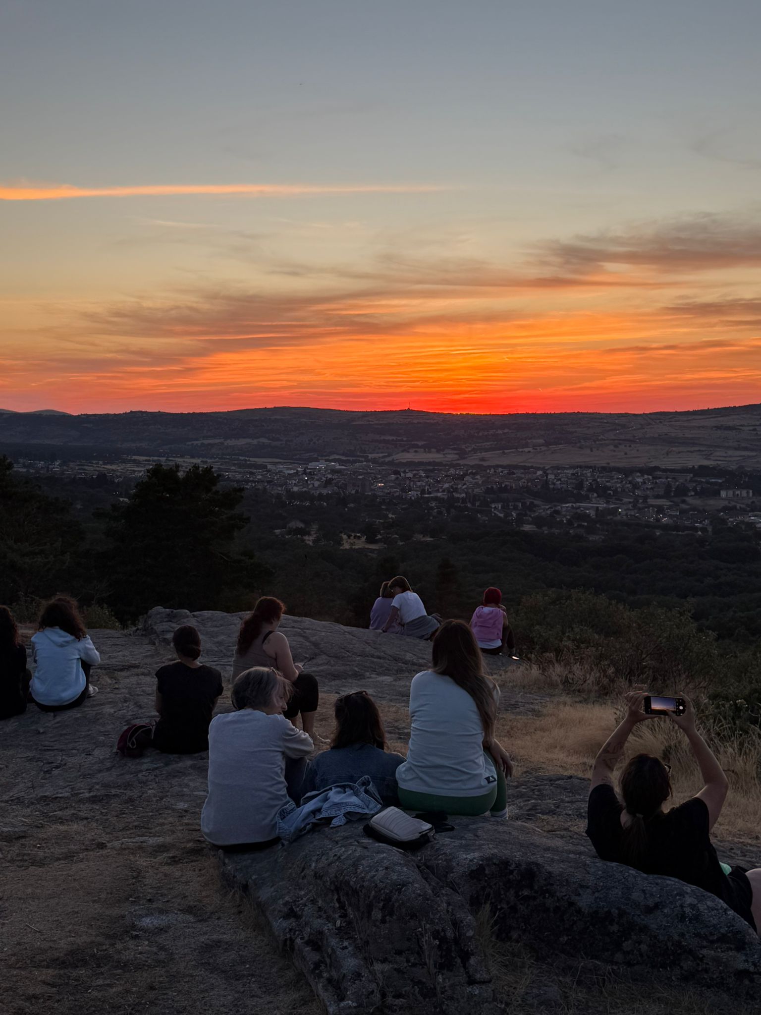 Grupo sentado en las rocas del pinar de El Espinar viendo el atardecer juntas
